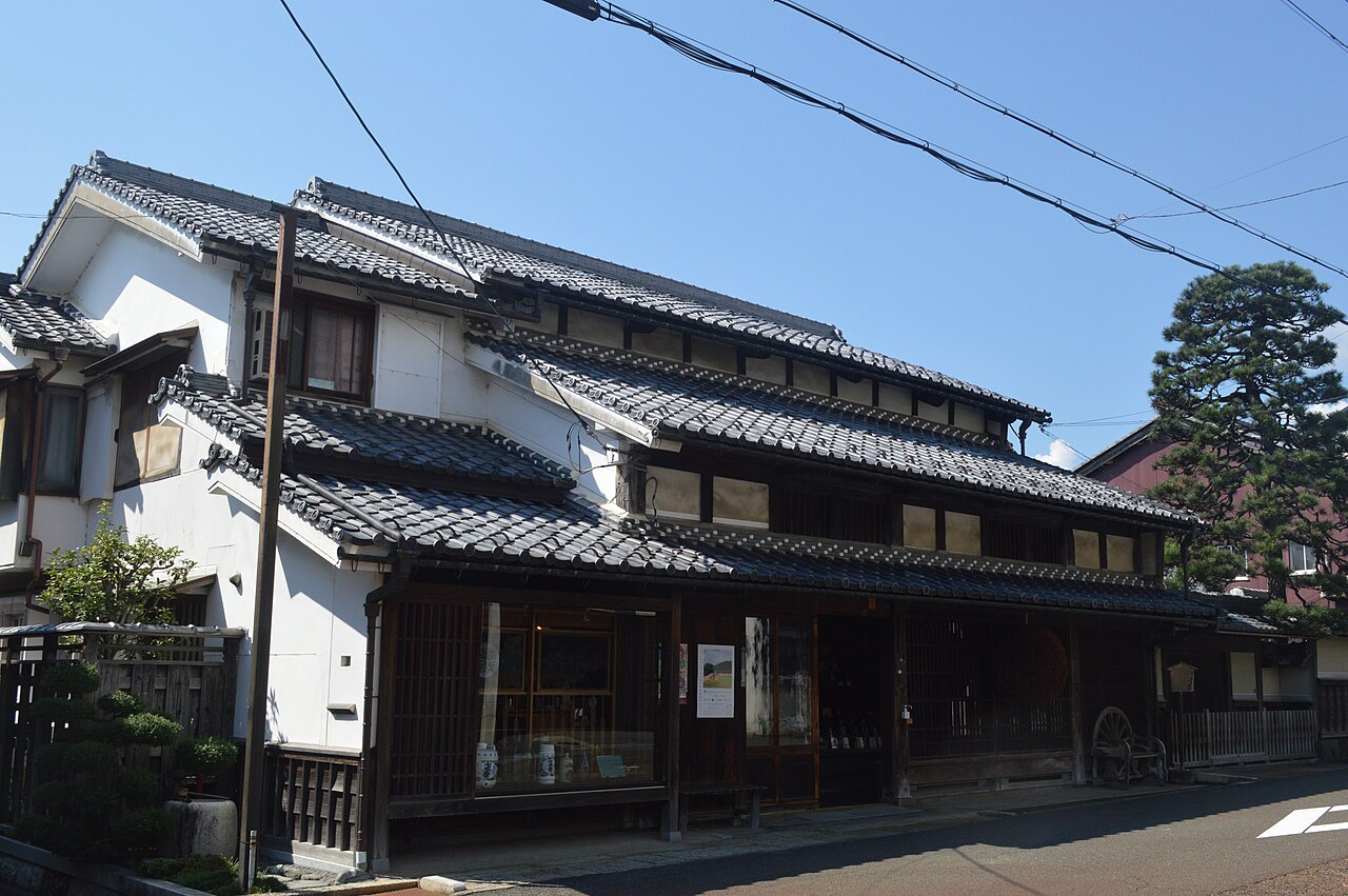 滋賀県長浜市木之本町の北国街道沿いに建つ冨田酒造。瓦屋根の二階建ての町家で、格子戸の軒先に丸い杉玉が下がっている