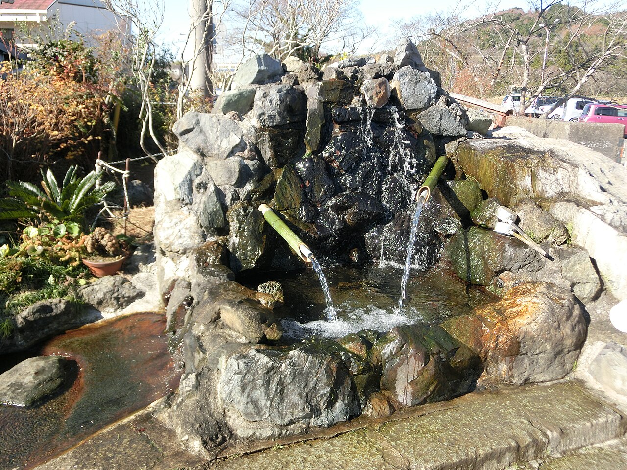 君津市久留里の自噴井戸。石を積んだ水場に2本の竹の管が差し込まれ、そこから水が勢いよく流れ落ちている