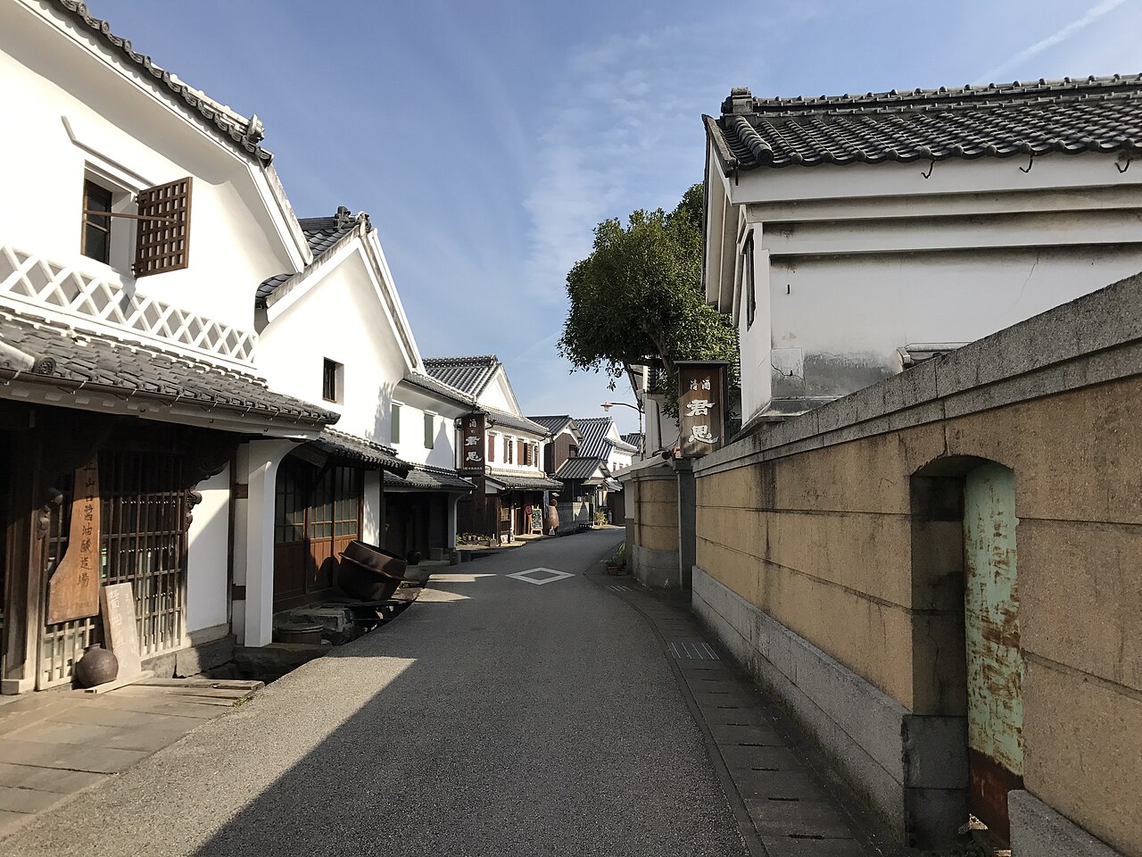 鹿島市浜中町八本木宿の酒蔵通り。白壁となまこ壁の蔵と瓦屋根の町家が細い通りの両側に並び、軒先に木の看板が下がっている